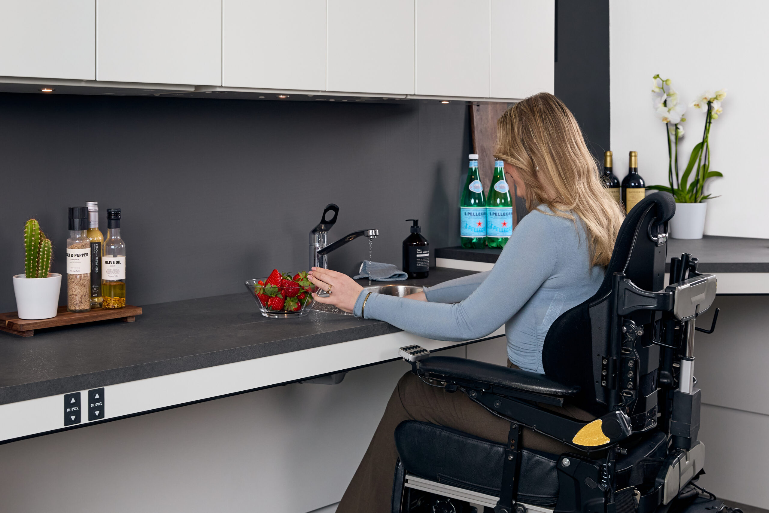 Wheelchair user washing strawberries at a lowered, accessible Ropox kitchen countertop